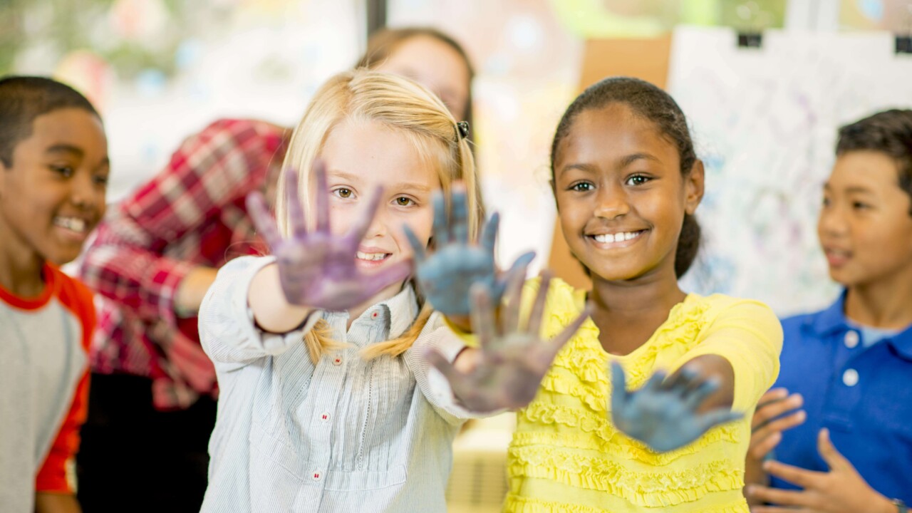Two girls showing off their finger painted hands.