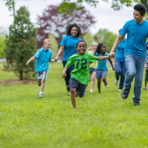 Adults and kids holding hands and racing.